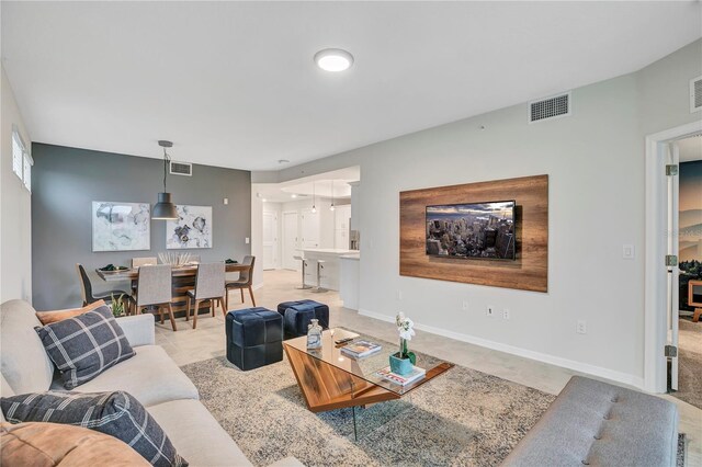 living area with visible vents, baseboards, and light colored carpet