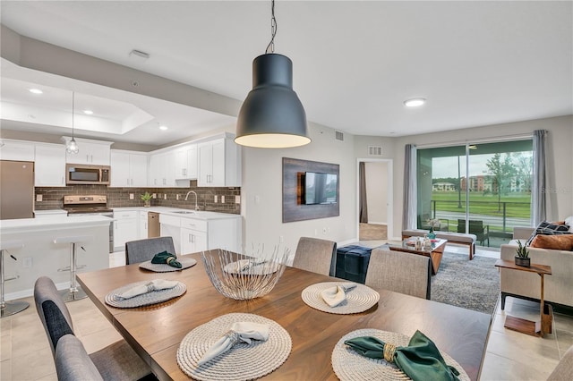 dining room with light tile patterned flooring, sink, and a raised ceiling