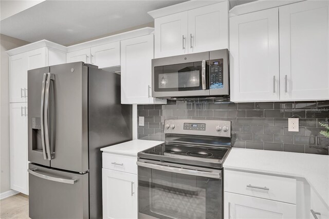 kitchen featuring stainless steel appliances, light countertops, backsplash, and white cabinetry