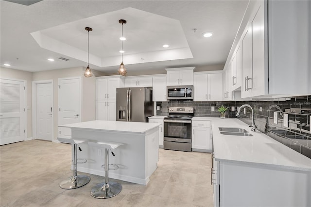 kitchen with white cabinets, stainless steel appliances, sink, and a raised ceiling