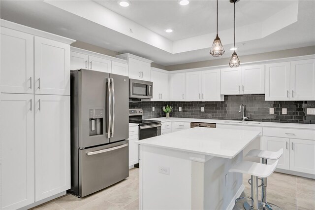 kitchen featuring a center island, a sink, decorative backsplash, white cabinetry, and appliances with stainless steel finishes