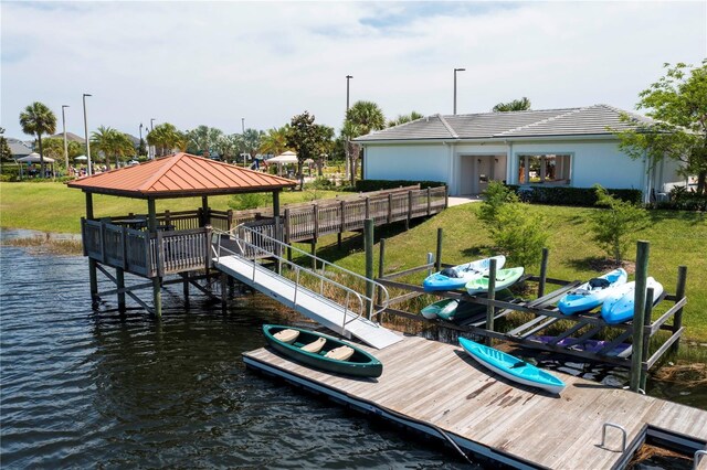 view of dock featuring boat lift, a gazebo, a water view, and a yard