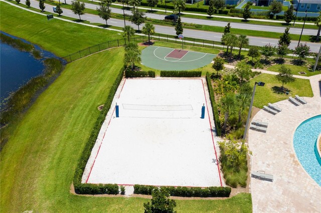 view of sport court featuring a lawn, a water view, and fence