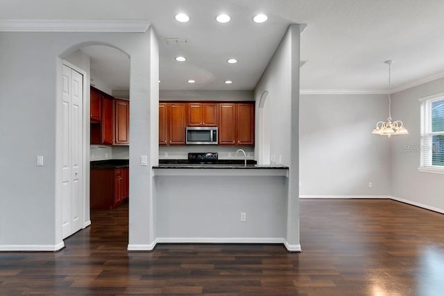 kitchen with arched walkways, stainless steel microwave, dark wood-type flooring, a peninsula, and pendant lighting