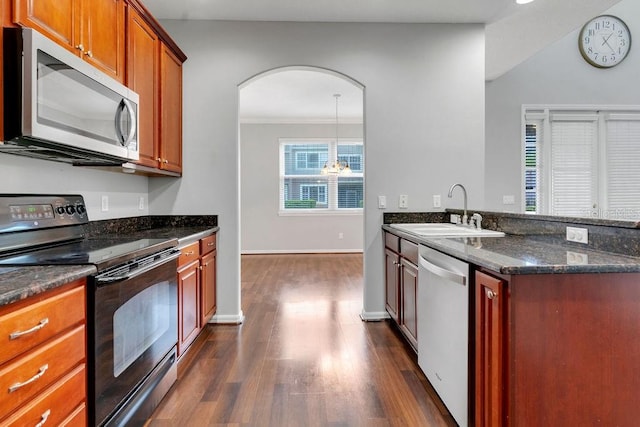 kitchen featuring dark stone counters, sink, dark hardwood / wood-style floors, stainless steel appliances, and pendant lighting