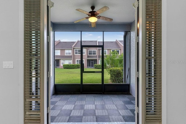 unfurnished sunroom featuring a ceiling fan