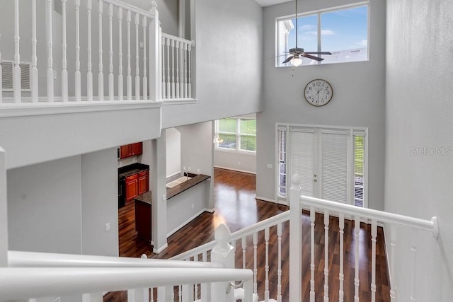 foyer with a towering ceiling, ceiling fan, baseboards, and dark wood-style flooring