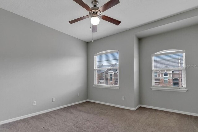 empty room with a wealth of natural light, carpet floors, and ceiling fan