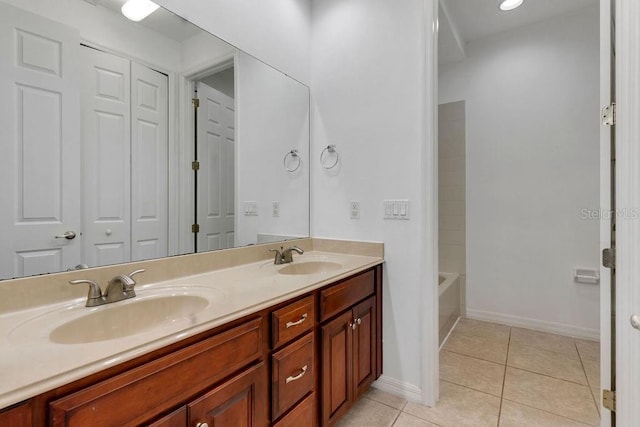 bathroom featuring double vanity, baseboards, a sink, and tile patterned floors