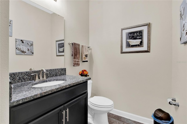 bathroom featuring toilet, vanity, and hardwood / wood-style flooring