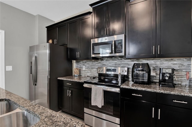 kitchen with appliances with stainless steel finishes, light stone counters, and decorative backsplash