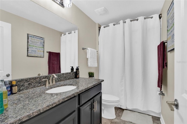 bathroom with toilet, vanity, and tile patterned floors