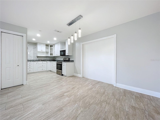 kitchen featuring visible vents, baseboards, black microwave, white cabinets, and stainless steel range