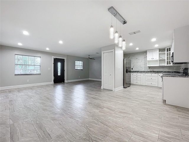 kitchen featuring visible vents, a ceiling fan, open floor plan, stainless steel fridge, and white cabinets