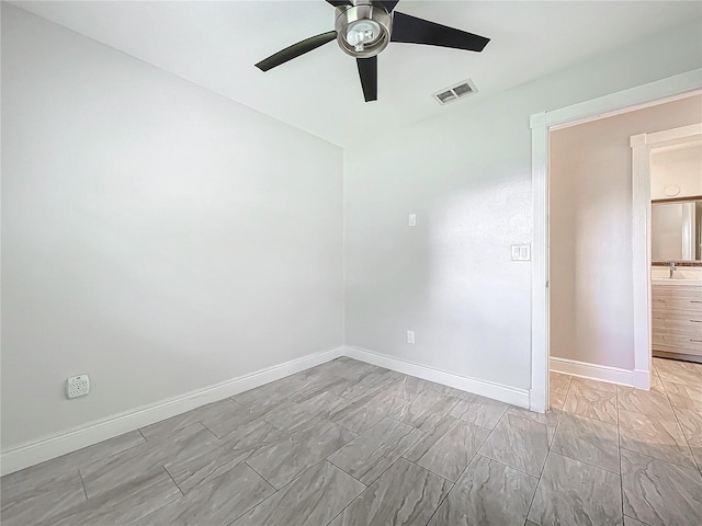 unfurnished room with ceiling fan, baseboards, visible vents, and a sink