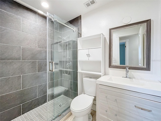 bathroom featuring visible vents, a stall shower, toilet, and vanity