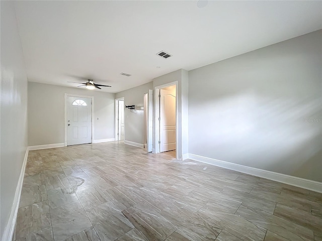 empty room featuring a ceiling fan, visible vents, and baseboards