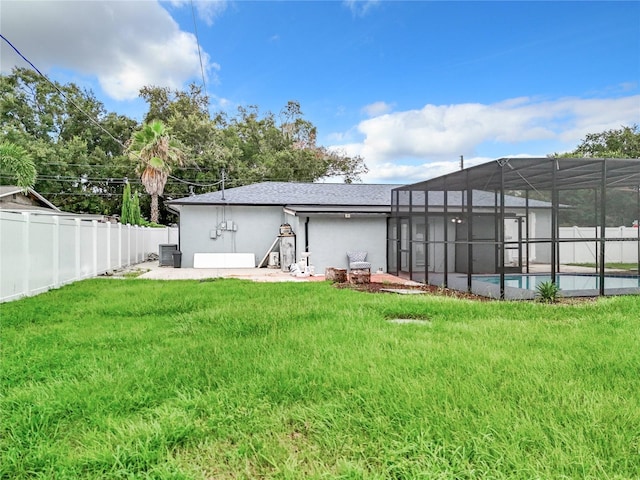 rear view of property with a fenced in pool, a lanai, stucco siding, a lawn, and a fenced backyard