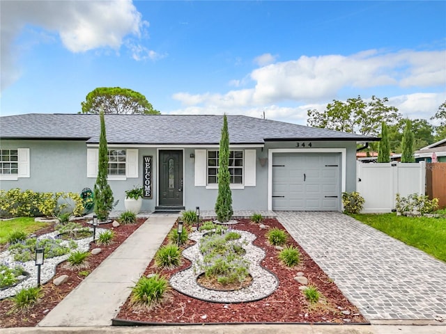 ranch-style home featuring fence, roof with shingles, stucco siding, decorative driveway, and a garage