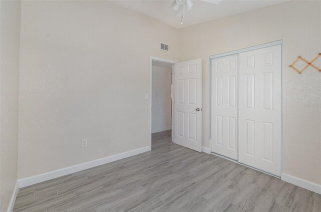 unfurnished bedroom featuring lofted ceiling, visible vents, baseboards, light wood-style floors, and a closet