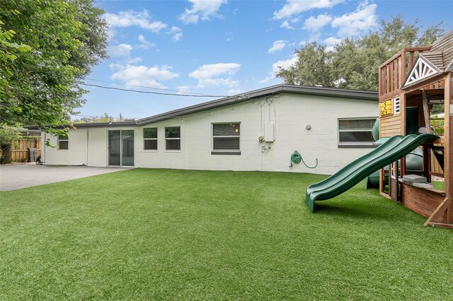 rear view of house featuring a patio area, fence, a playground, and a yard