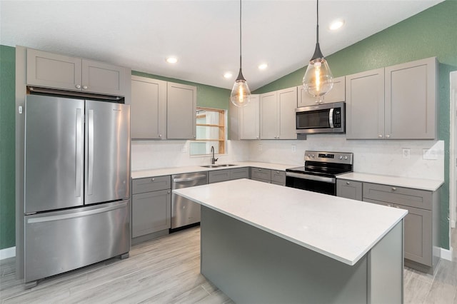 kitchen with appliances with stainless steel finishes, lofted ceiling, a center island, and sink