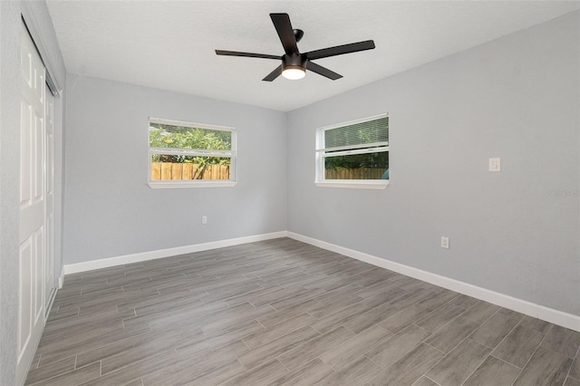 spare room featuring ceiling fan, a textured ceiling, wood finished floors, and baseboards