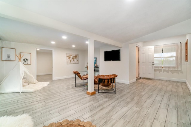 interior space featuring lofted ceiling, light wood-style flooring, and baseboards