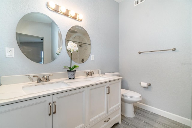 full bathroom with visible vents, a sink, toilet, and double vanity