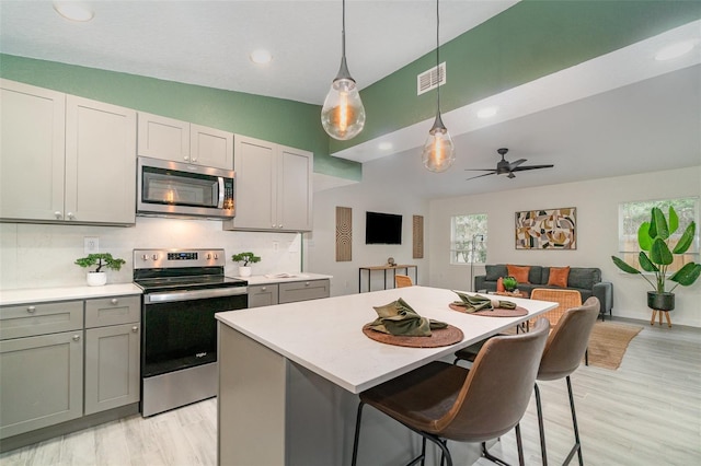 kitchen with visible vents, a kitchen island, appliances with stainless steel finishes, light countertops, and gray cabinetry