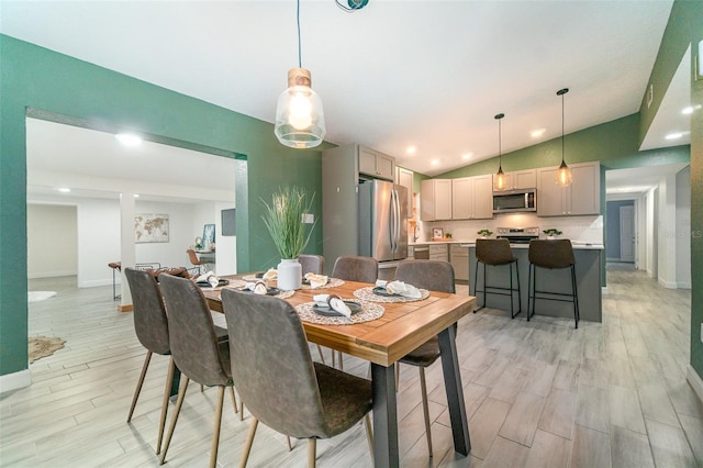 dining area featuring lofted ceiling, light wood-style flooring, and baseboards