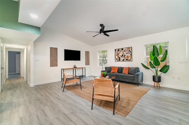 living room featuring ceiling fan, vaulted ceiling, light wood-style flooring, and baseboards