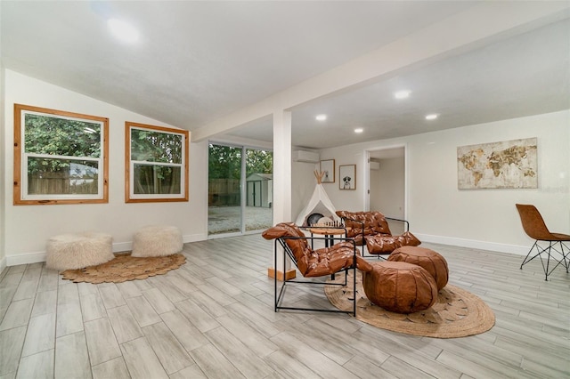 living area featuring lofted ceiling, an AC wall unit, wood finished floors, and baseboards