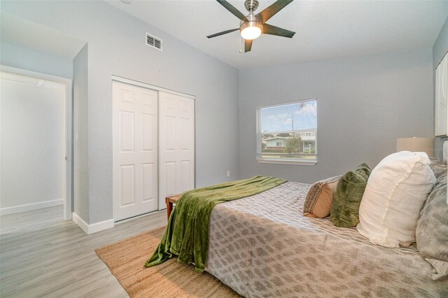 bedroom with light wood finished floors, lofted ceiling, a closet, visible vents, and ceiling fan