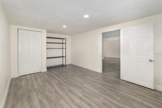 unfurnished bedroom featuring recessed lighting, light wood-style flooring, and baseboards