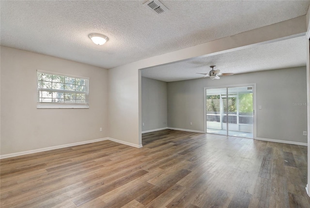 empty room with wood finished floors, visible vents, and baseboards