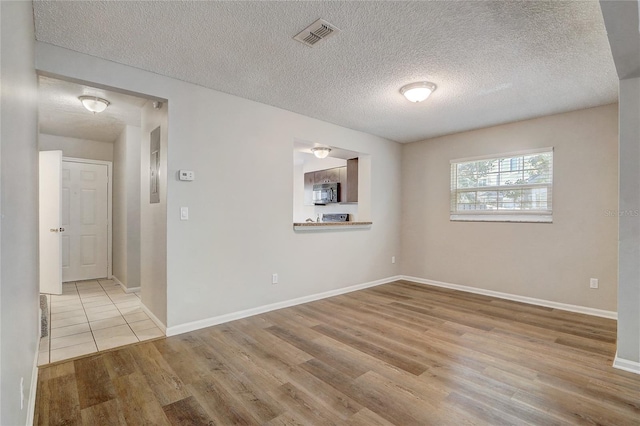 unfurnished room with visible vents, light wood-style flooring, baseboards, and a textured ceiling