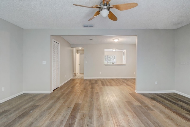 empty room featuring light wood-style floors, visible vents, and baseboards