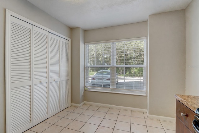 unfurnished bedroom featuring a closet, baseboards, and light tile patterned floors