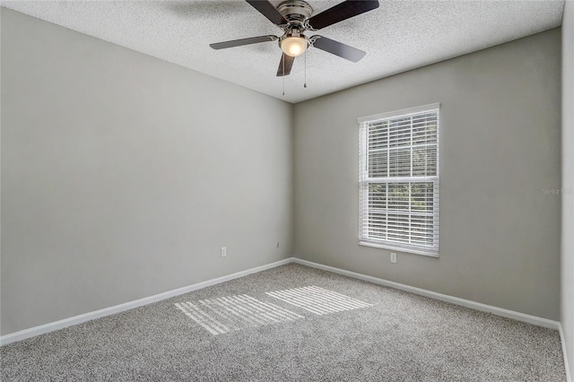 carpeted spare room featuring a textured ceiling, ceiling fan, and baseboards