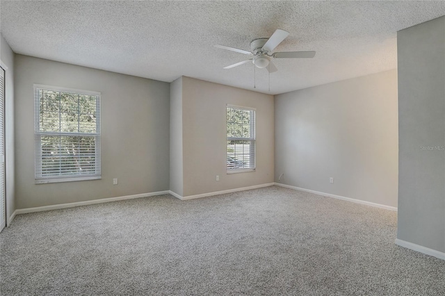 empty room with a ceiling fan, light carpet, a textured ceiling, and baseboards