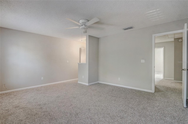 spare room featuring a textured ceiling, light colored carpet, a ceiling fan, baseboards, and visible vents