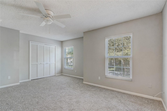 unfurnished bedroom with a ceiling fan, a closet, light carpet, and baseboards