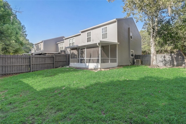 back of house featuring central air condition unit, a sunroom, a fenced backyard, and a lawn