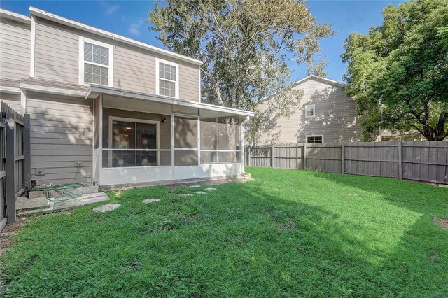 back of house with a sunroom, a fenced backyard, and a yard