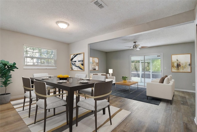 dining room featuring visible vents, dark wood finished floors, a textured ceiling, and baseboards