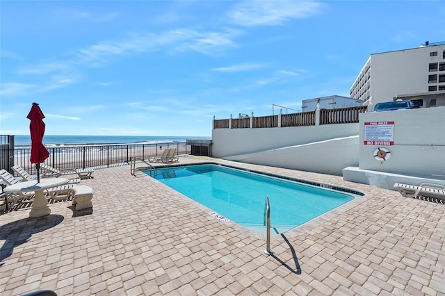 view of pool featuring a water view and a patio