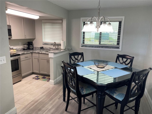 dining area with a chandelier, light wood-style flooring, and baseboards