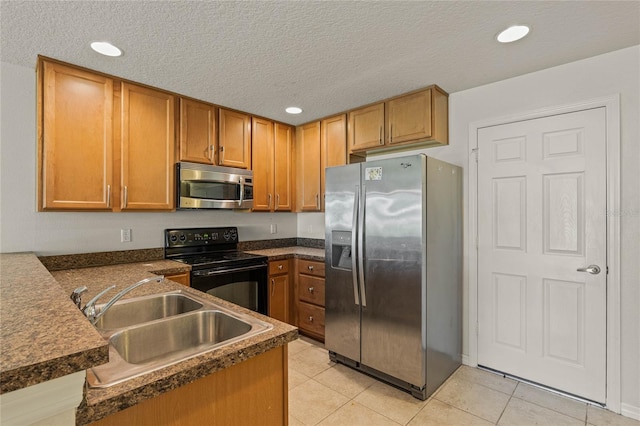 kitchen with light tile patterned floors, appliances with stainless steel finishes, sink, and a textured ceiling