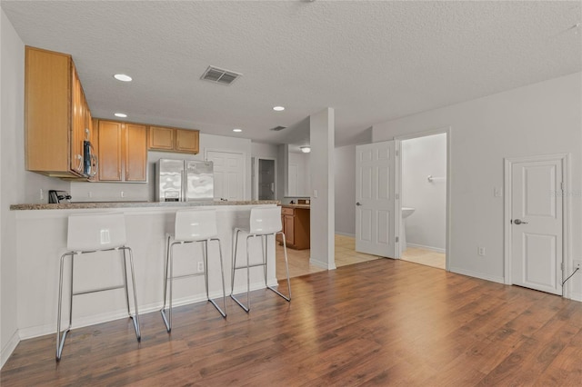 kitchen featuring light wood-type flooring, appliances with stainless steel finishes, and a textured ceiling